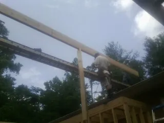 Carpenter setting a ridge beam over a new addition frame — Ice Dam Removal by Roofing Brothers in Coyanosa