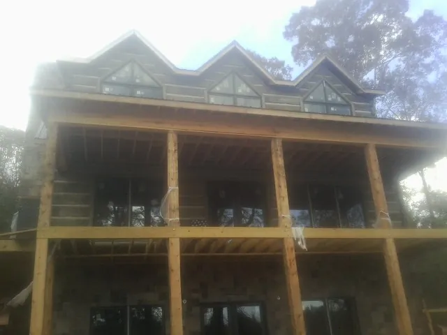 Dormers and porch framing on a large log home under construction — Roof Coating work by our crew in Coyanosa