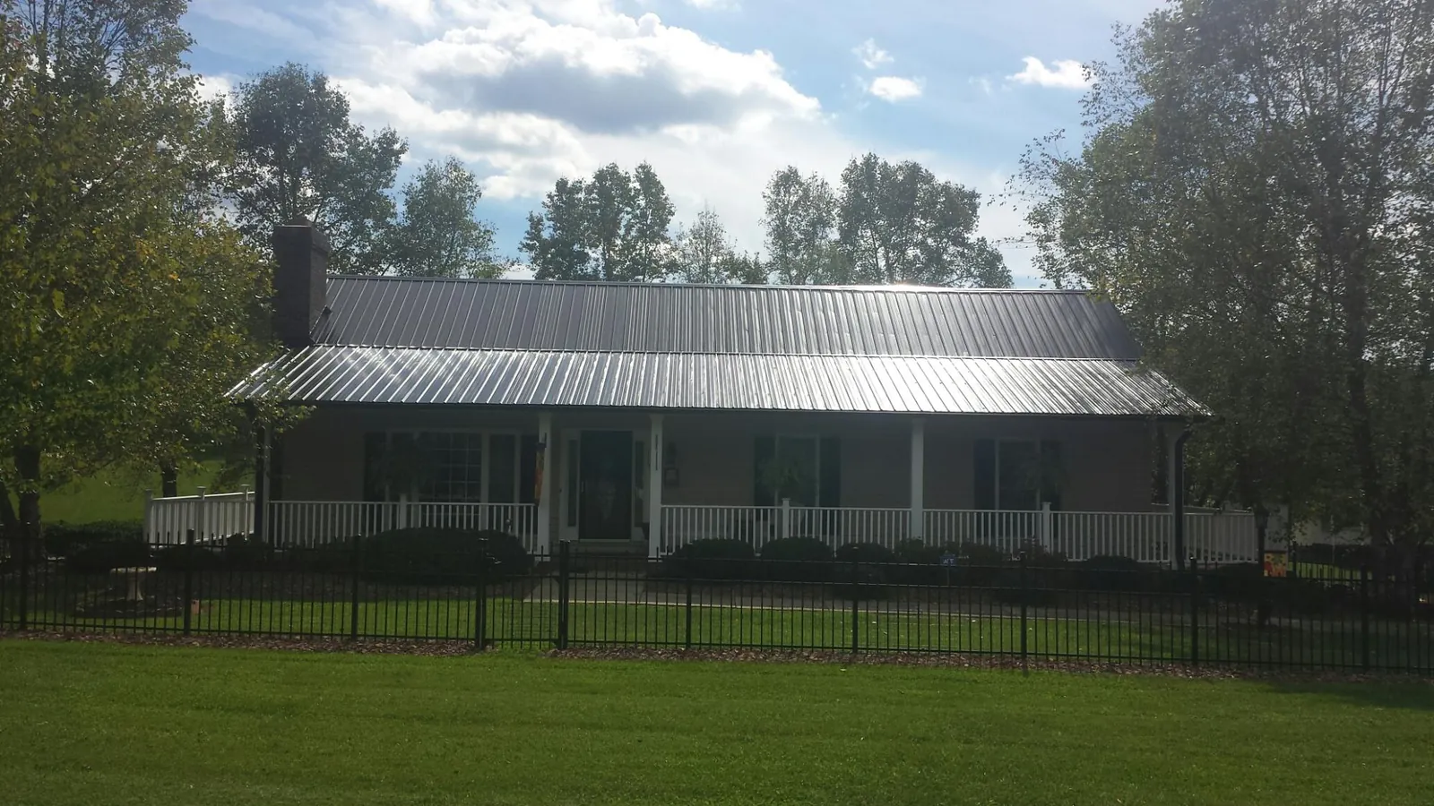 Gray metal roof on a brick ranch with a full width front porch — Gutter Guard Installation work by our crew in Coyanosa
