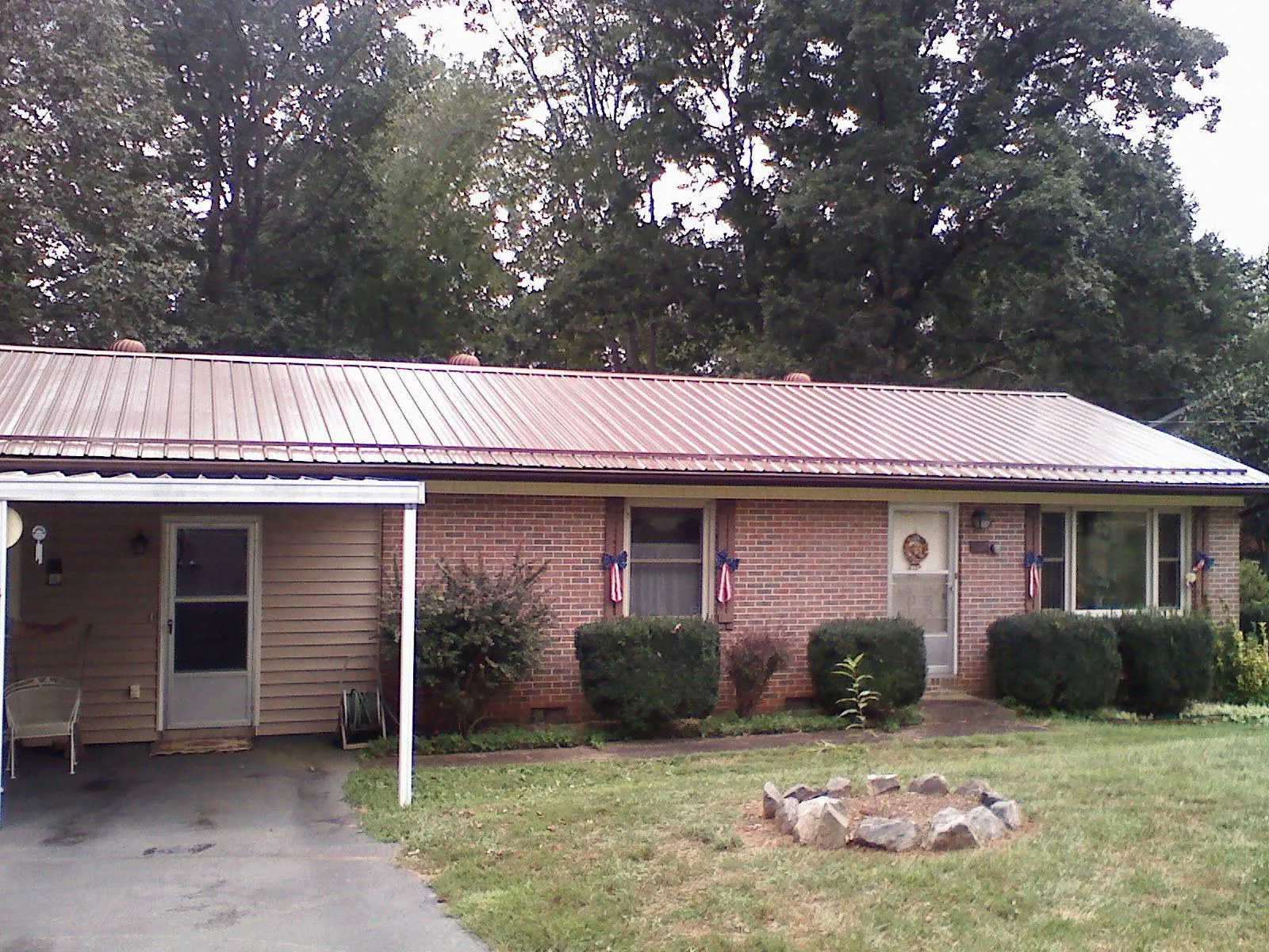 Bronze metal roof and carport on a brick ranch home — Roof Repair work by our crew in Coyanosa