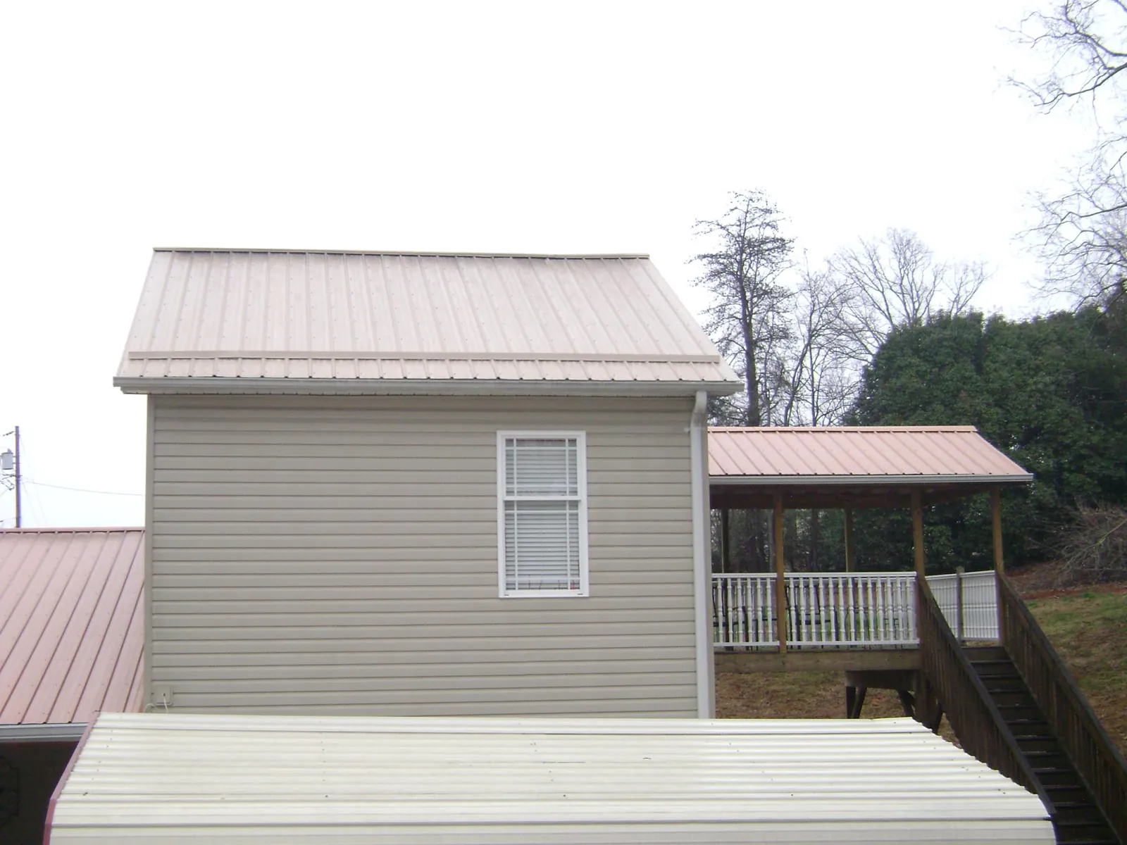 Tan metal roofs on a two story addition and attached porch, from a Roof Replacement job in Coyanosa