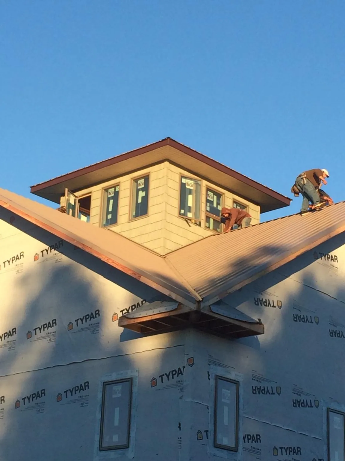 Roofers working around a rooftop cupola on a new metal roof at sunset — Roof Waterproofing in Coyanosa by Roofing Brothers